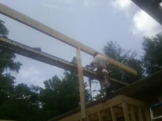 Carpenter setting a ridge beam over a new addition frame — Ice Dam Removal by Roofing Brothers in Buckner