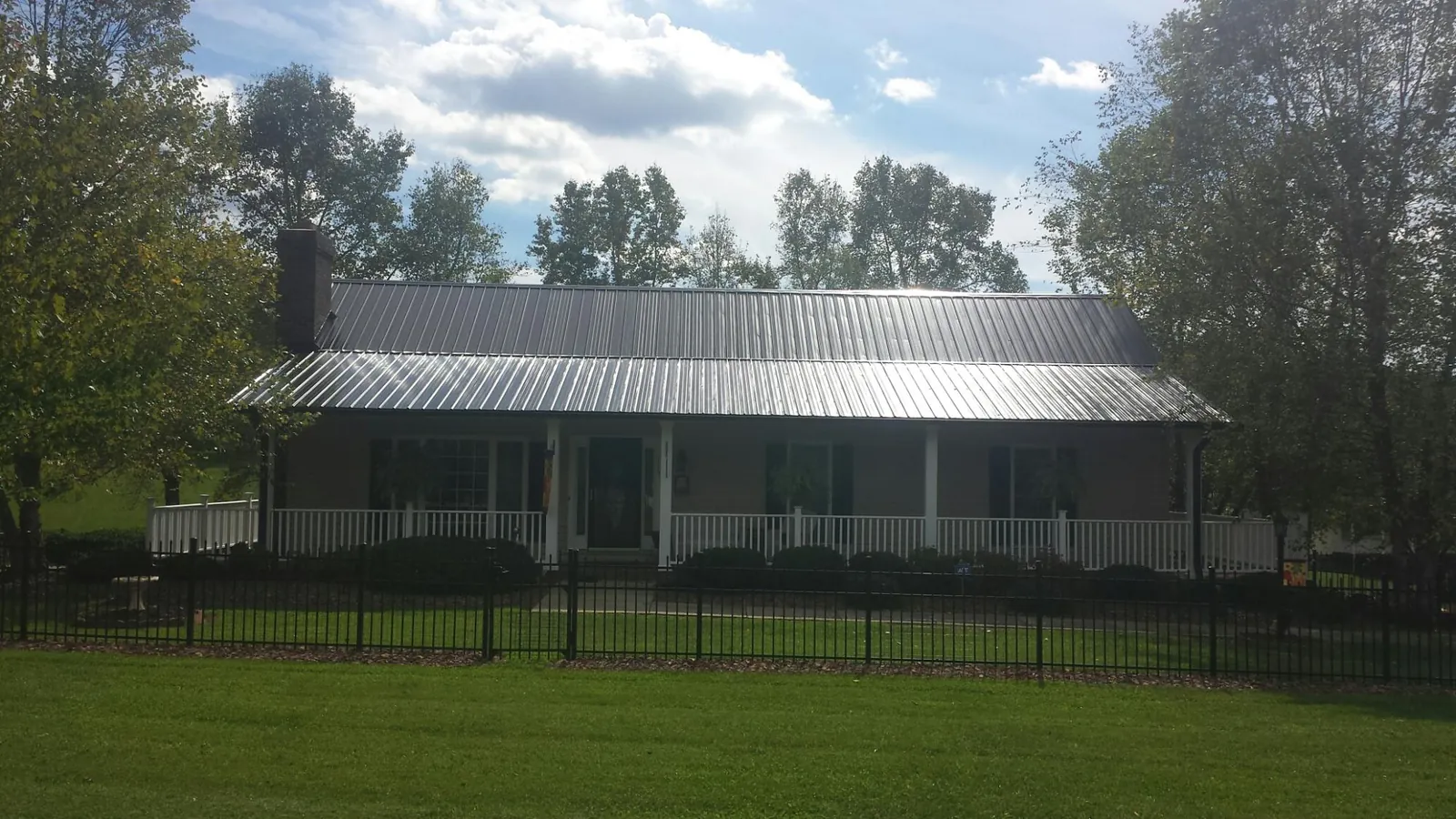 Gray metal roof on a brick ranch with a full width front porch — Gutter Guard Installation work by our crew in Buckner