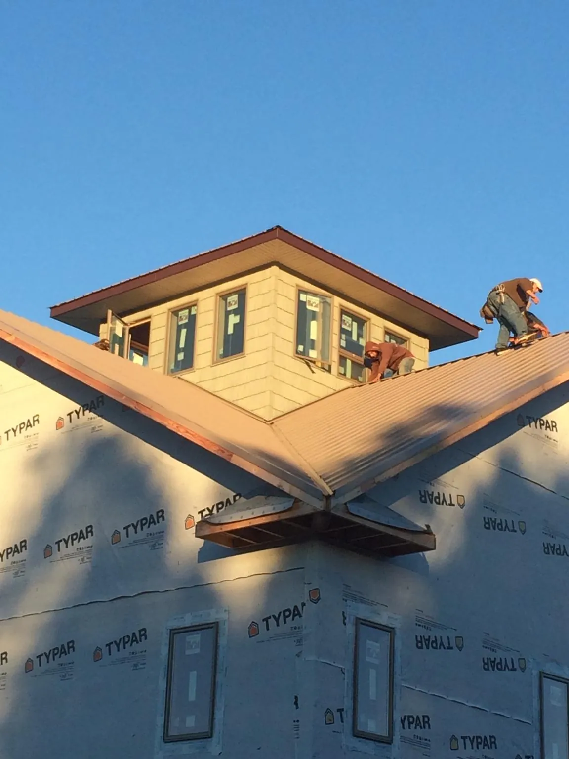 Roofers working around a rooftop cupola on a new metal roof at sunset — Roof Waterproofing in Buckner by Roofing Brothers
